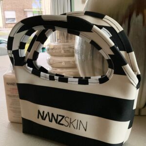 The Nanzskin Riviera Pouch is a sleek, architecturally inspired beauty  companion, designed for the discerning skincare lover. Crafted in signature  black and white neoprene with a sculptural checkered handle, it’s perfect  for housing your Nanzskin essentials, whether on your vanity, in your tote,  or by your side while traveling. Lightweight, structured, and unmistakably  bold, the Riviera Pouch is elegance in motion. 